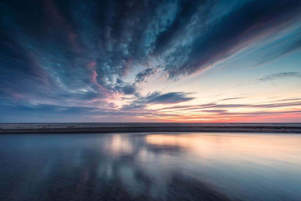A sky reflecting over water at dusk.